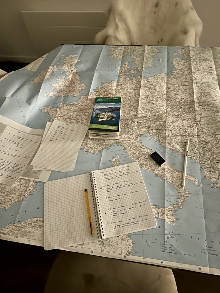Carte papier avec carnet et stylo lors de la préparation d’un itinéraire de road trip en Europe